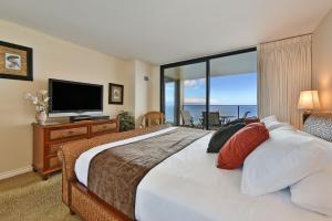 une chambre avec un grand lit et une télévision dans l'établissement Mahana 1217 Oceanfront, à Lahaina