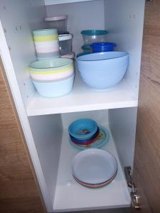 ein weißes Regal mit Schüsseln und Tellern darauf in der Unterkunft Camping le soleil d'or Mobil Home in Montalivet-les-Bains + 1 Foto