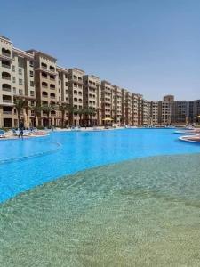 une grande piscine d'eau bleue en face des bâtiments dans l'établissement Aqua View, à El Qasaba esh Sharqīya