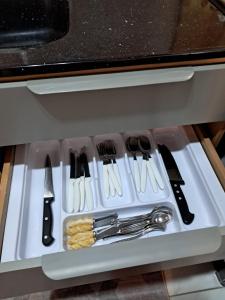 Un cajón con utensilios en una bandeja blanca. en Chalé aconchegante à 300mts do mar, en Arroio do Silva