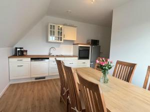 a kitchen with a wooden table with a vase of flowers at Premium Landhauswohnung in Neuenkirchen