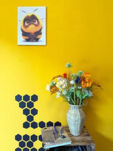 a yellow wall with a vase of flowers on a table at Bienenhaus in Troisdorf