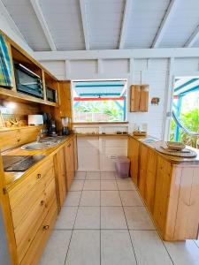 a kitchen with wooden cabinets and a large window at Secteur prisé, bungalow Corail, Résidence CASA BOUBOU in Sainte-Anne