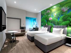 a hotel room with two beds and a painting on the wall at ibis Styles Sepang KLIA in Sepang