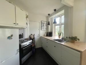 a kitchen with white cabinets and a stove top oven at Apartment in heart of Amager in Copenhagen