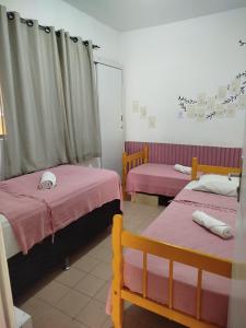 a room with three beds with pink sheets at A casa é Sula Hostel Maceió para mulheres in Maceió +18 photos