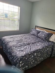 a bedroom with a bed with a black comforter and a window at Minutes to Beach, Mayo Clinic, Hot Tub, King Bed, Free PPV in Jacksonville
