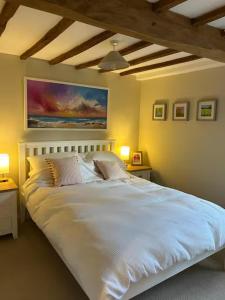 a bedroom with a large white bed with two lamps at Charming cottage in Urchfont