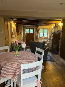 a dining room with a table with a vase of flowers on it at Charming cottage in Urchfont