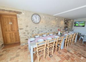 a dining room with a table and a clock on the wall at La Tournerie, Gîte 10 pers piscine près Puy du Fou in Saint-Fulgent