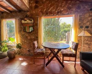 a dining room with a table and chairs and a window at Casa de piedra con jardin y pileta - privada in Los Hornillos