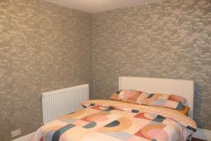 1 dormitorio con cama y pared con papel pintado en Private Room in a Modern Victorian Style House, en Chatham