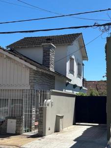 a white house with a gate and a fence at Pasala Lindo in Tandil