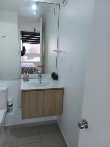 a bathroom with a sink and a toilet and a mirror at Departameto comodo Coquimbo HA in El Cerrillo