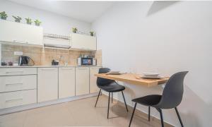 a kitchen with white cabinets and a wooden table and chairs at דירת הפרימיום - 5 דקות נסיעה מהים in Ashqelon