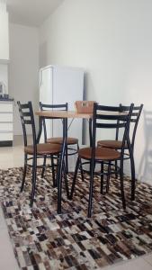 Short stay Osório في أوسوريو: طاولة طعام مع أربعة كراسي وثلاجة