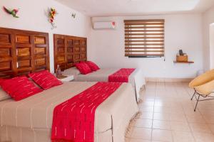 two beds in a room with red pillows at Casa Rincón Bonito in Puerto Escondido