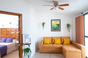 a bedroom with a couch and a bed with yellow pillows at Casa Rincón Bonito in Puerto Escondido
