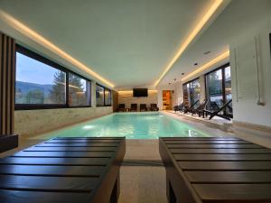 a swimming pool in a house with windows at Planinska kuca Popovic 3 in Ljuboš