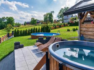 ノヴィ・タルクにあるVilla in Nowy Targ with Mountain Views & Poolの2つのプールと椅子、庭のあるパティオ