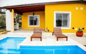 a yellow house with two chairs and a pool at Complejo la Pasionaria in Villa Parque Siquiman +3 photos