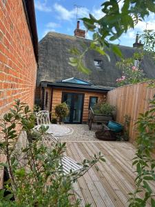 a backyard with a wooden deck and a house at Charming cottage in Urchfont