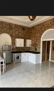 a kitchen with white appliances and a stone wall at Villa Nile Queen -guest house in Luxor