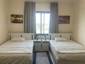 two twin beds in a room with a window at Seaside Two Bedroom Charming Apt in Salalah +50 photos