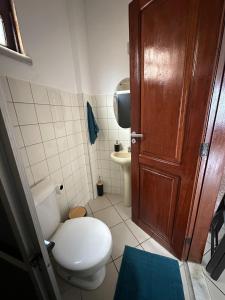 Un baño con inodoro y puerta de madera. en Apartamento Janelas do Atlântico Praia do Atalaia PA, en Salinópolis