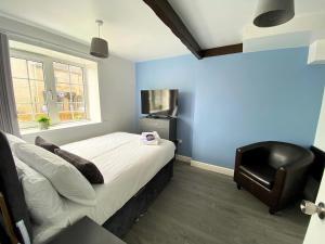 a bedroom with a bed and a black chair at Thornton Road Lodge -Room 1 in Bradford