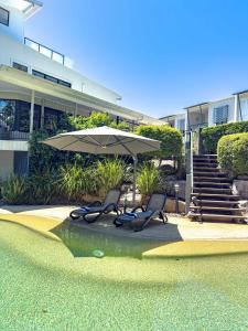 two chairs and an umbrella in front of a building at Villa Essencia - Luxurious 4br, Gated, Private, Pool in Coolum Beach