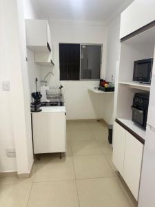 a white kitchen with a sink and a microwave at Studio apartment - Bom Retiro - S05 in Ipatinga +11 photos