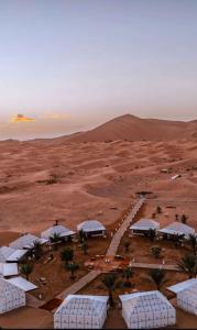 an aerial view of a desert with a group of white buildings at Infinity sahara camp in Merzouga