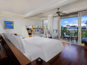 une chambre avec un grand lit blanc et un balcon dans l'établissement Swissôtel Sanya Yalong Bay, à Sanya