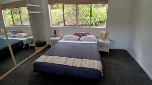 deux lits dans une chambre avec deux fenêtres dans l'établissement Peaceful Country Home Between Brisbane & GC, à Wolfdene