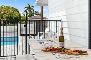 a table with a bottle of wine and wine glasses at 'Short Break' - Luxurious Coastal Retreat with Pool and BBQ in Urangan