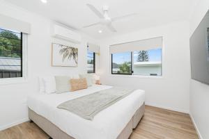 a white bedroom with a large bed and two windows at 'Short Break' - Luxurious Coastal Retreat with Pool and BBQ in Urangan