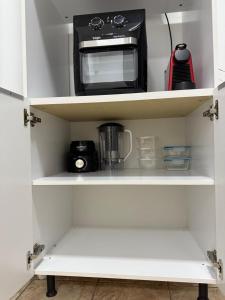 a kitchen shelf with a microwave and a toaster oven at Studio Apartment - Bom Retiro - S04 in Ipatinga
