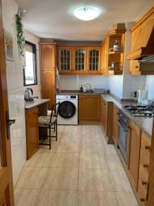 Casa Blanca - apartamento en Gandia في غانديا: مطبخ مع دواليب خشبية وغسالة صحون
