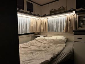 1 cama no hecha en una habitación con 2 ventanas en Fully Equipped Caravan 1, en Gentofte 8 fotos más