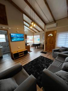 uma sala de estar com sofás e uma TV de tela plana em Cabaña Puerta a la Patagonia em Chaitén