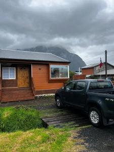 um camião preto estacionado em frente a uma casa em Cabaña Puerta a la Patagonia em Chaitén