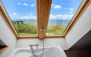 a bathroom with a window and a bath tub with a view of the ocean at 4 Bedroom Beach Front Home In Vinderup in Vinderup