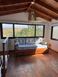 een slaapkamer met een bank in een kamer met ramen bij La Colina de Villa Yacanto in Villa Yacanto