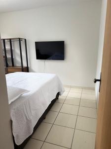 a bedroom with a bed and a flat screen tv at Kitnet - Centro - Ipatinga in Ipatinga +15 photos