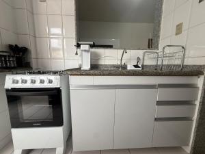 a white kitchen with a stove and a sink at Kitnet - Centro - Ipatinga in Ipatinga