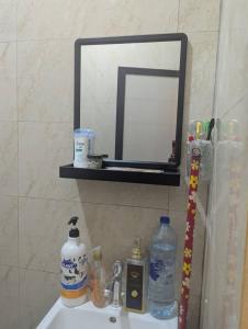 a bathroom sink with a mirror and bottles on it at Ocean Breeze Apartments in Dar es Salaam