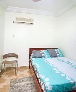 1 cama con edredón azul y 1 silla en una habitación en Two Bedrooms Standby Generator DSTV Netflix W-iFi, en Takoradi