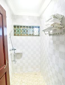 een badkamer met een douche en witte betegelde muren bij Two Bedrooms Standby Generator DSTV Netflix W-iFi in Takoradi