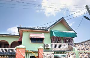 een groen huis met een balkon aan de zijkant bij Two Bedrooms Standby Generator DSTV Netflix W-iFi in Takoradi